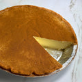 A Milktart in an aluminum pie tin with cinnamon dusted over the top.